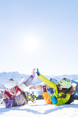Skifahrer und Snowboardfahrer liegen auf der Piste